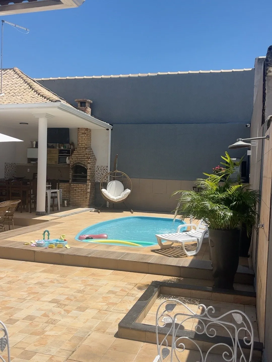 Área da piscina com palmeira e espreguiçadeiras